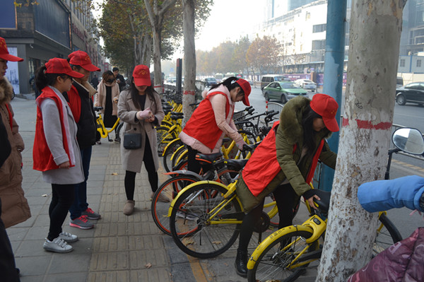 把路边乱摆、乱放的单车主动扶起有序摆好